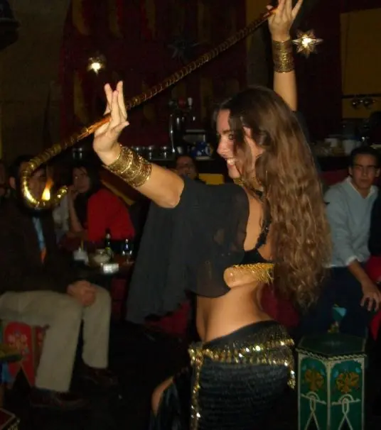 Ana in a black costume dancing with a cane, under star-shaped lanterns