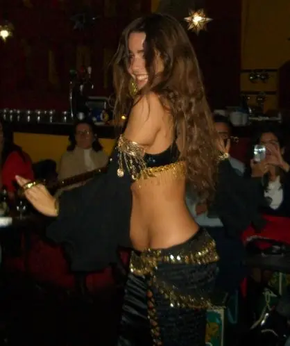 Ana in a black costume with a cane, smiling over her shoulder