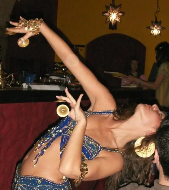 Ana in a blue beaded costume, leaning back with finger cymbals