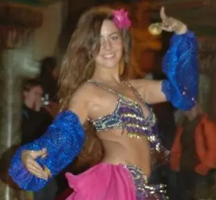 Ana smiling in blue sleeves and a pink skirt, with a flower in her hair