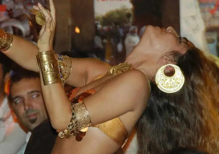 Ana leaning back with finger cymbals, cuffs and a large gold earring