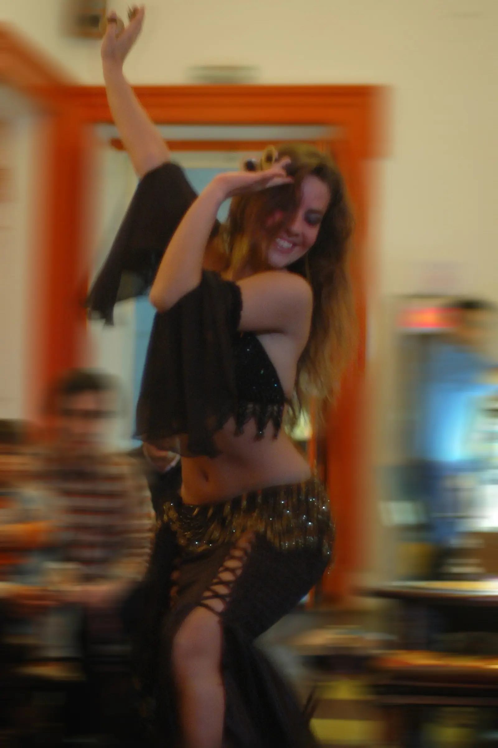 Ana smiling on stage, framing her head with both arms, in a slit skirt