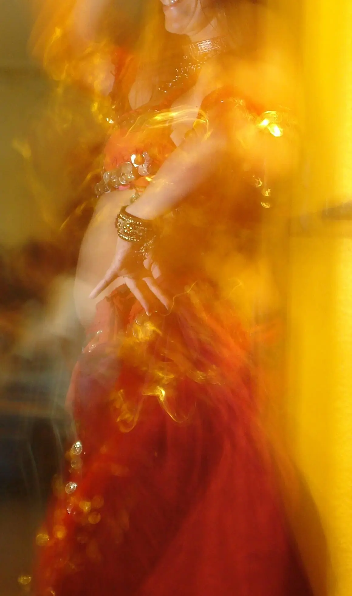 Ana moving fast in a red and gold costume, under warm light