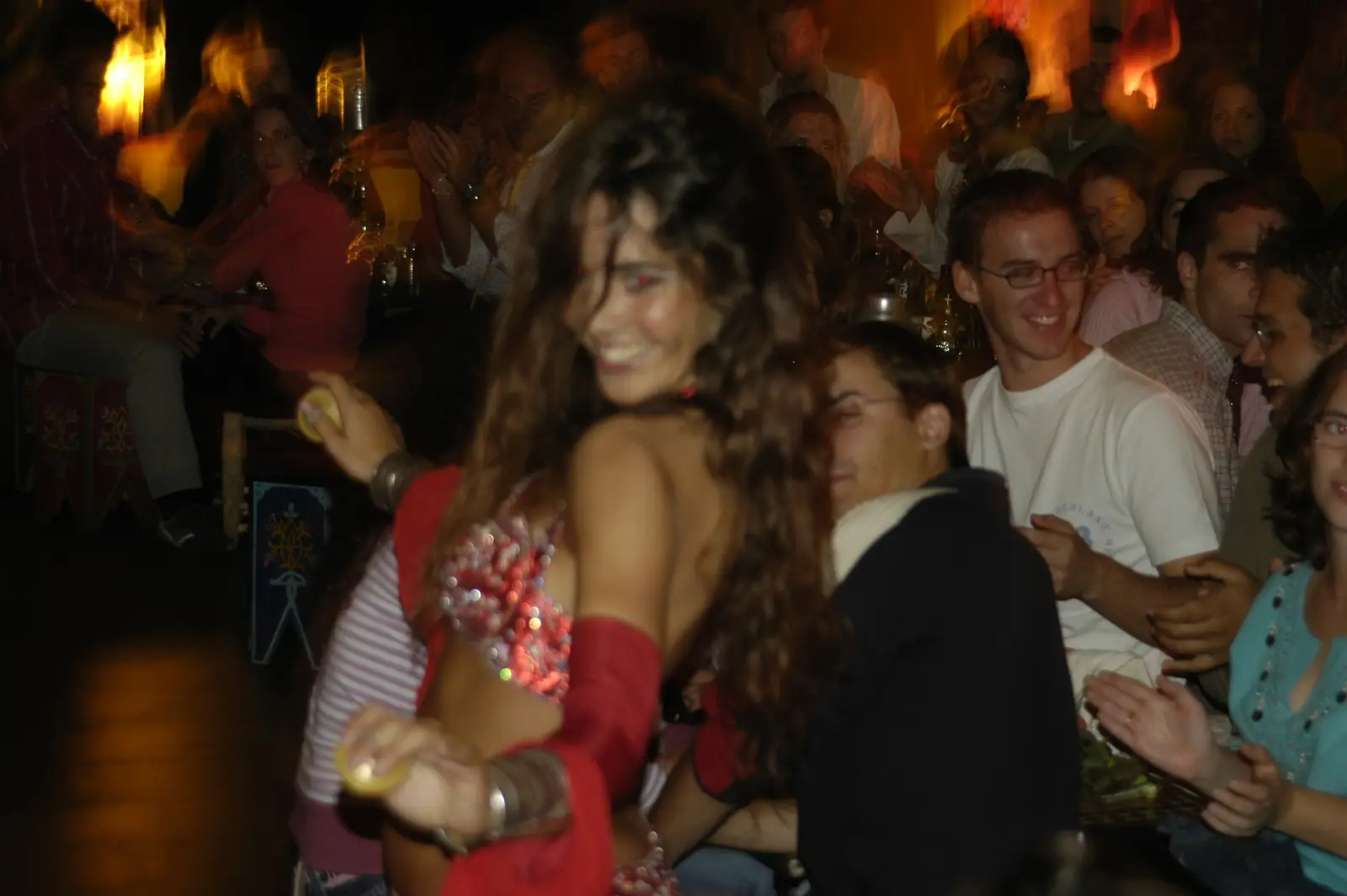 Ana smiling with finger cymbals in a red costume, in front of the audience