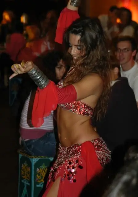 Ana in a red costume with finger cymbals, dancing among the audience