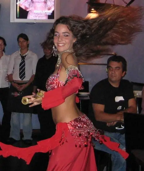 Ana smiling in a red costume with her hair flying, at a dinner show