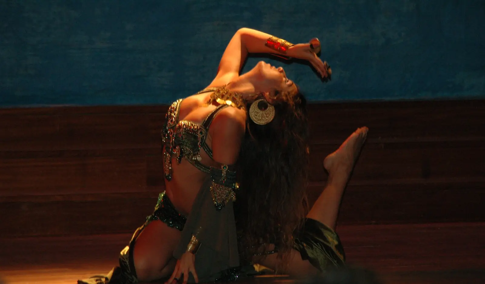 Ana dancing on the stage floor, leaning back with one arm over her face, under warm light