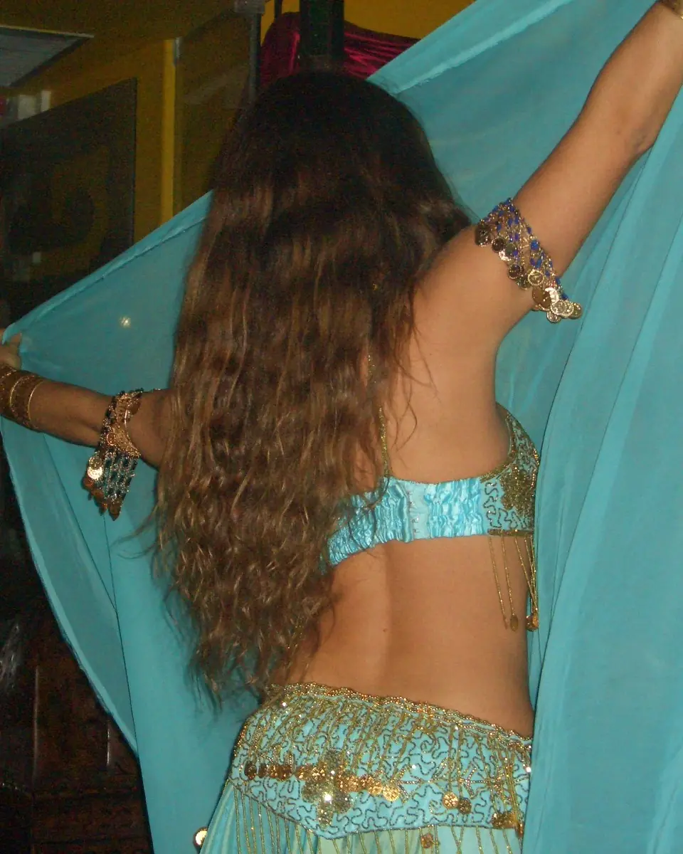 Ana seen from behind opening a turquoise veil, with long curly hair